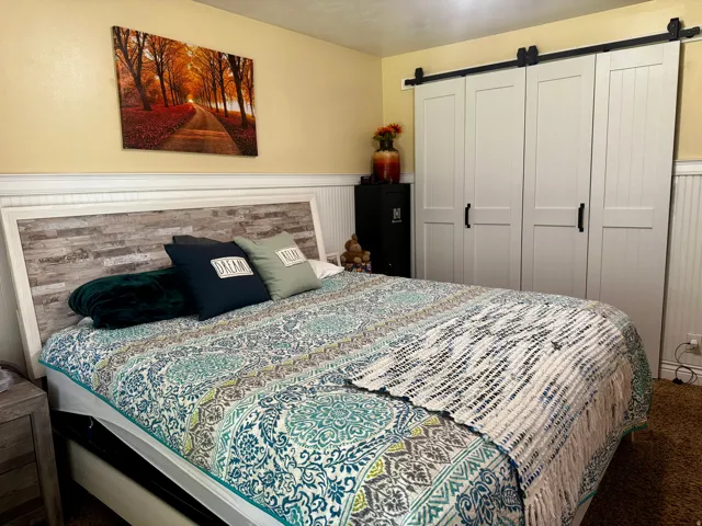 Board and batten wall paneling, white crown molding, light-colored wall paint, and barn door style closet doors with black hardware