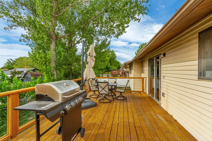 Expansive wood deck with a wood railing and wire infill, featuring a sliding glass door entry and beige horizontal siding