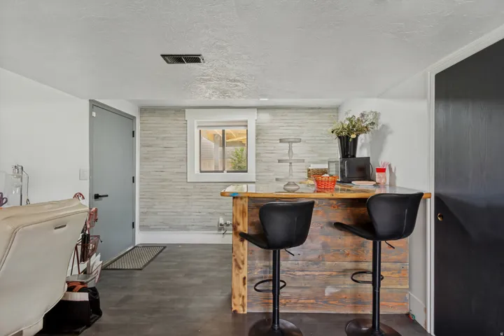 LVP flooring, accent wall with horizontal paneling, built-in bar with wood-finish paneling, and an interior window
