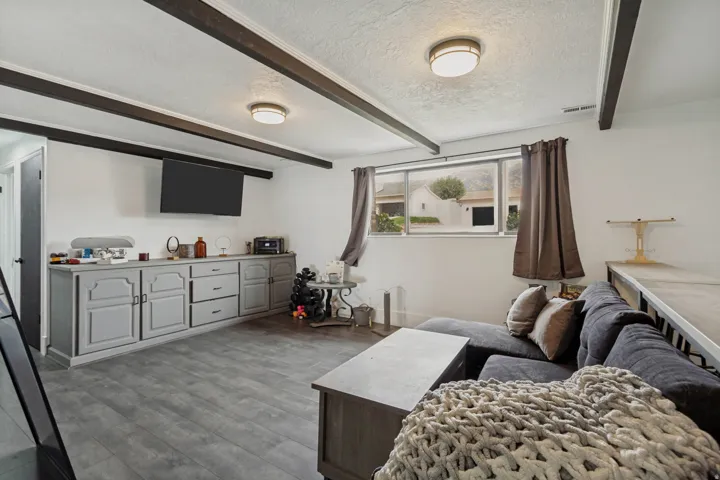 LVP flooring, exposed ceiling beams, built-in cabinetry with drawers, and a large window