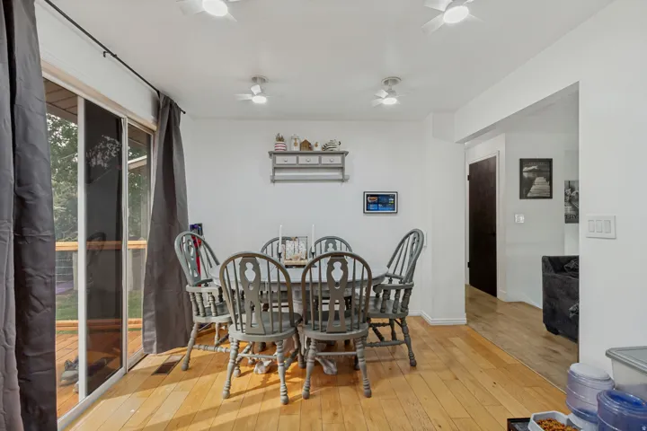 Hardwood-style flooring, white walls, multiple ceiling-mounted light fixtures, and a sliding glass door to an exterior deck