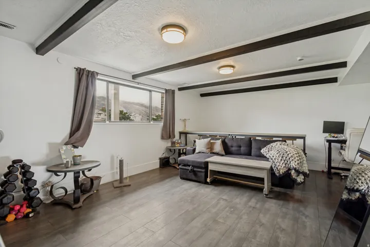 LVPflooring, exposed ceiling beams, recessed lighting, and a large window