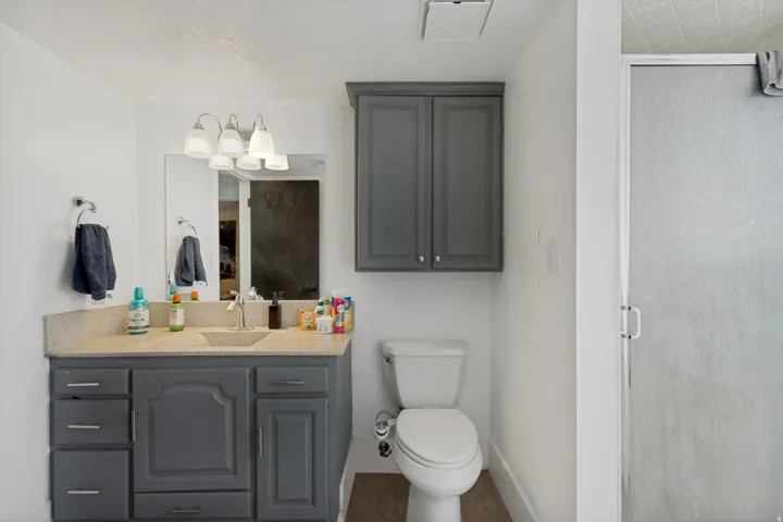 Vanity with a light-toned countertop, under-mount sink, and a multi-bulb light fixture