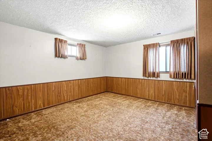 Recessed windows with natural light, textured ceiling, and wood-panel wainscoting