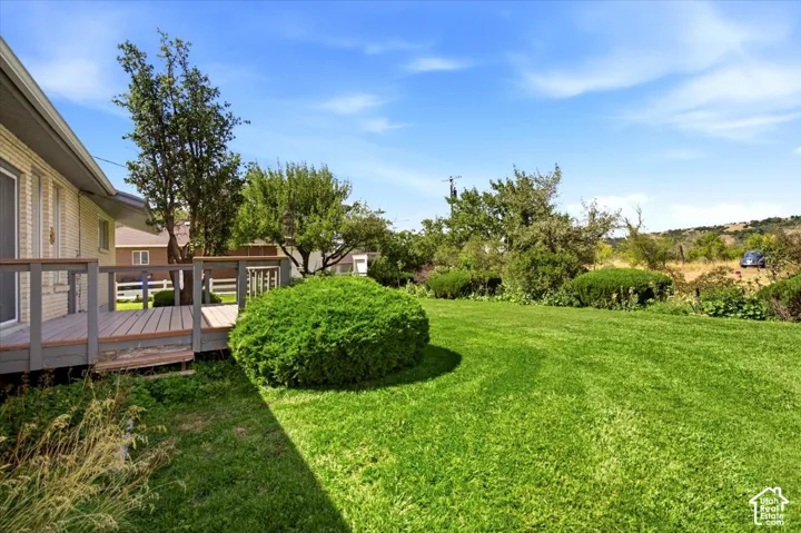 Expansive green lawn with established shrubbery, featuring a wood-finish deck with railings