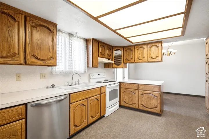 Kitchen featuring wood-finish cabinetry, white countertops, a stainless steel dishwasher, and a white electric range