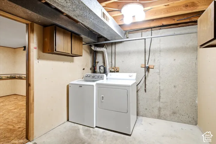 Utility area with exposed concrete walls, overhead lighting, and built-in wood-finish cabinetry