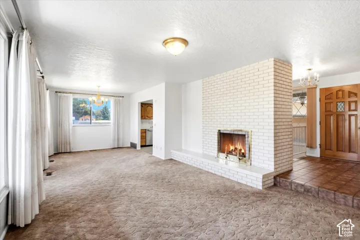 Expansive room with white brick fireplace and hearth, wood-paneled entry door, and tiled entry flooring