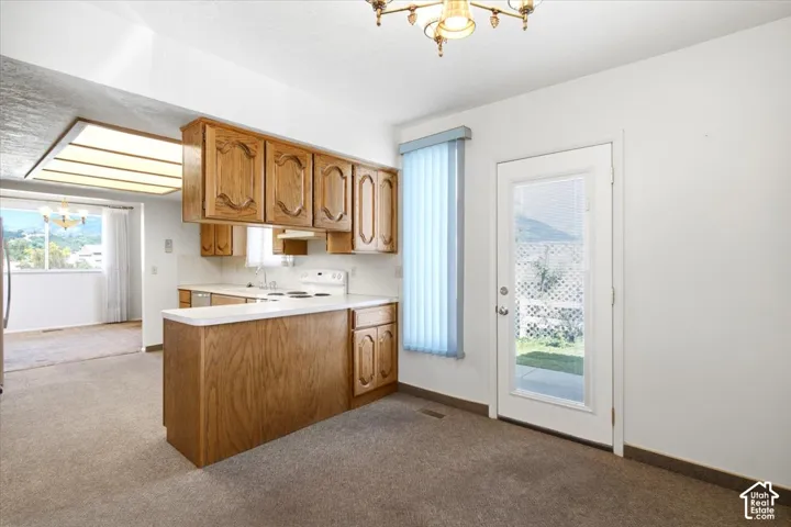 Kitchen space featuring wood-finish cabinetry, white countertops, a white electric range, and a breakfast bar