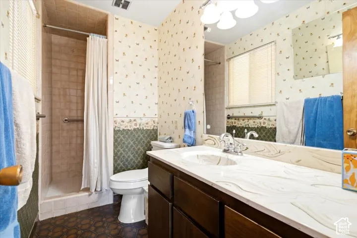 Full vanity mirror with sconce lighting, integrated sink with chrome faucet, and a tile-surround shower with grab bar