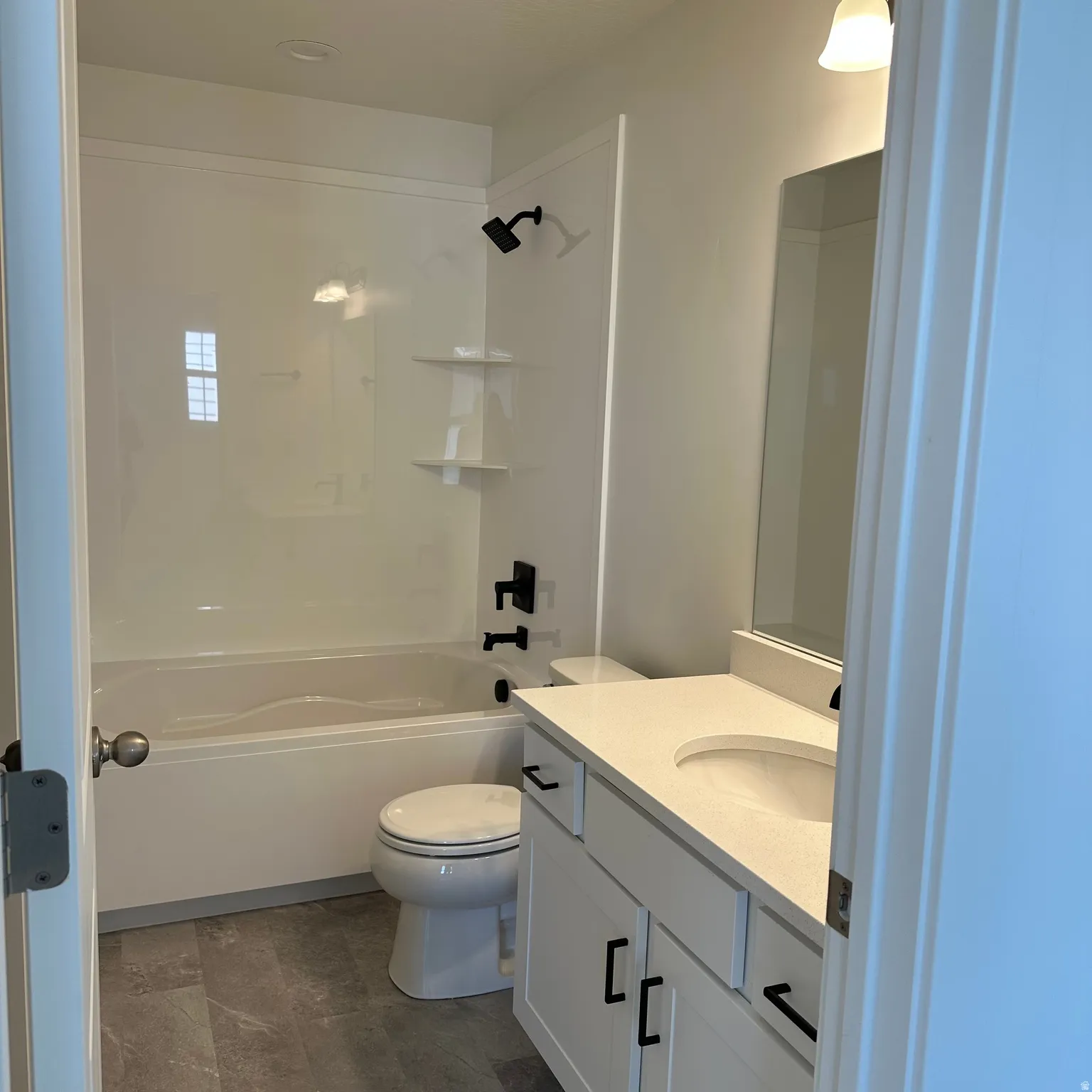White vanity with black hardware, integrated sink, and light-colored countertop