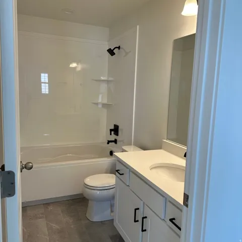 White vanity with black hardware, integrated sink, and light-colored countertop