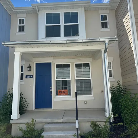 Two-story exterior with a covered porch, contrasting blue entry door, and prominent upper-level windows