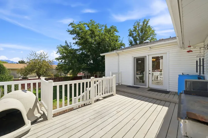 Expansive deck with white railing, double glass doors, and a partial mountain backdrop
