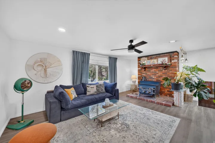Recessed lighting, wood-finish flooring, brick fireplace, wood-burning stove, and ceiling fan