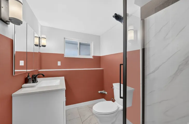 White vanity with a rectangular sink, matte black faucet, and light-toned countertop