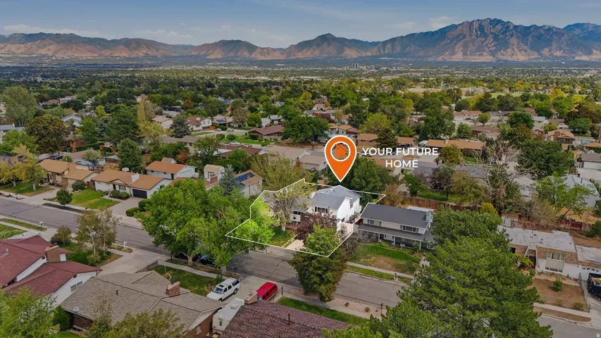 Aerial perspective of a suburban neighborhood with established trees and mountain backdrop