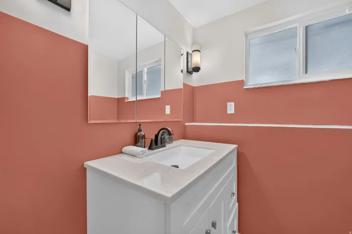 White vanity with a light-toned countertop, integrated sink, and dark-toned faucet
