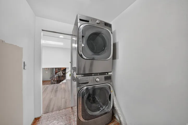 Stacked stainless steel laundry appliances with drum doors, set on a tiled floor
