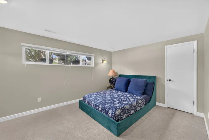 Neutral tone wall paint, light color carpeting, horizontal window, white interior door, and wall-mounted sconce