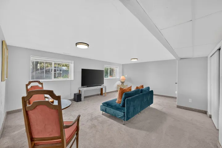 Spacious room with light gray walls, light gray carpet, and multiple windows
