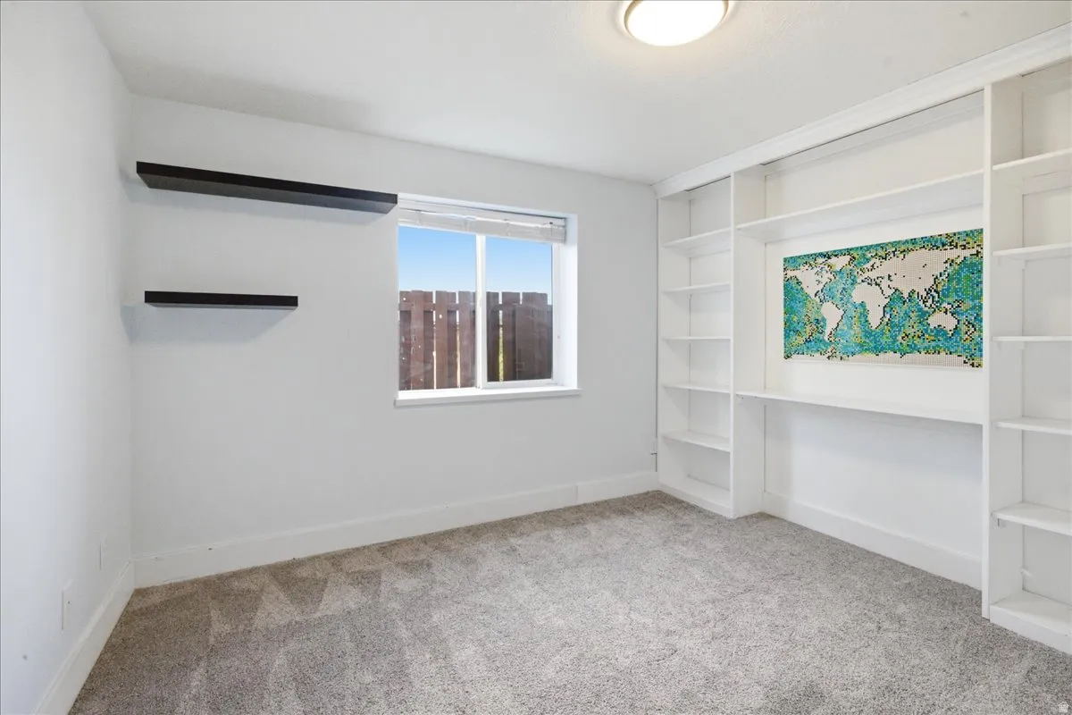 Built-in shelving unit, integrated desk space, two floating shelves, window with white trim, and a flush mount ceiling light