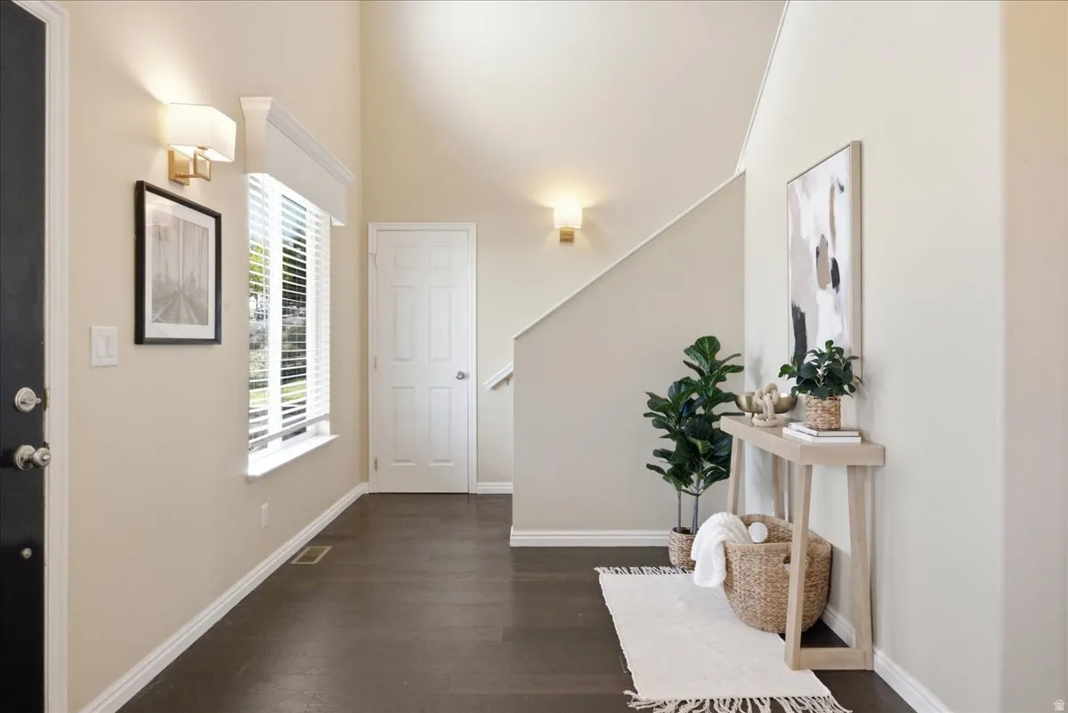 Vaulted ceiling entry with wood-finish flooring, a multi-pane window, and a paneled door