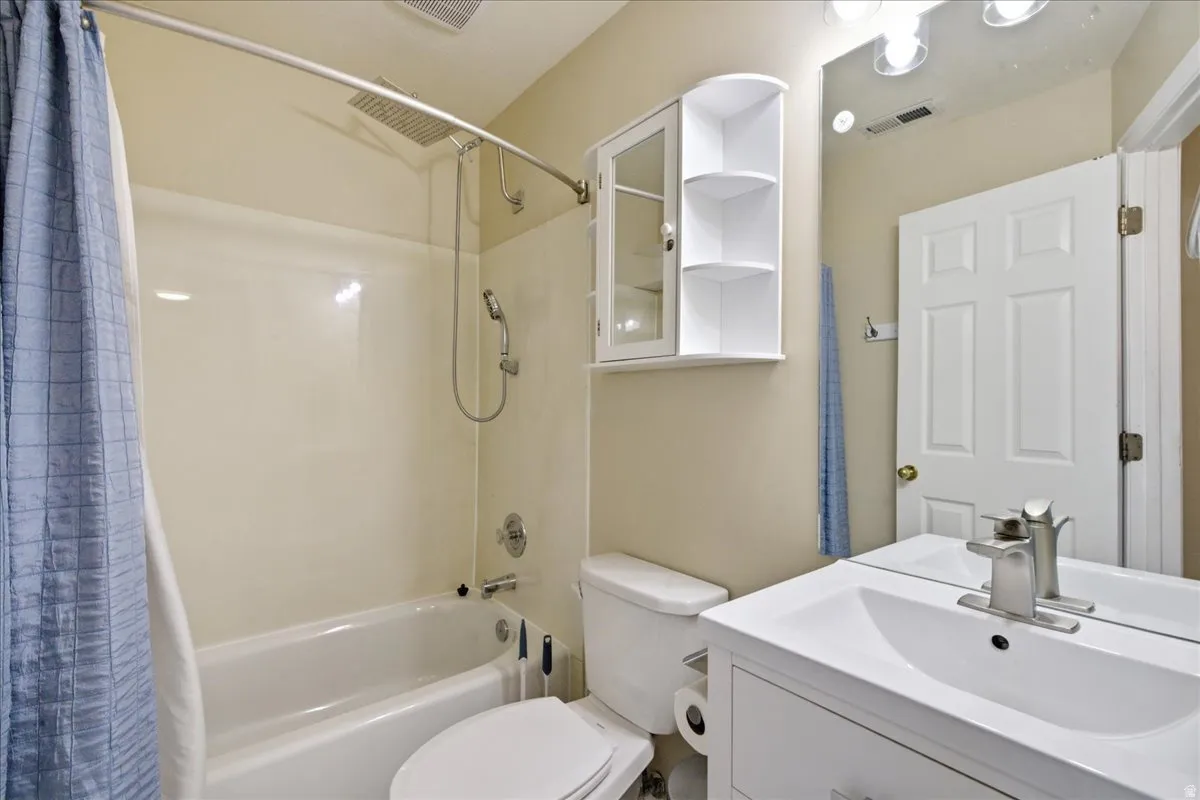 Bathroom featuring a white vanity with integrated sink, brushed nickel faucet, large mirror, and shower/tub combination with a rainfall showerhead