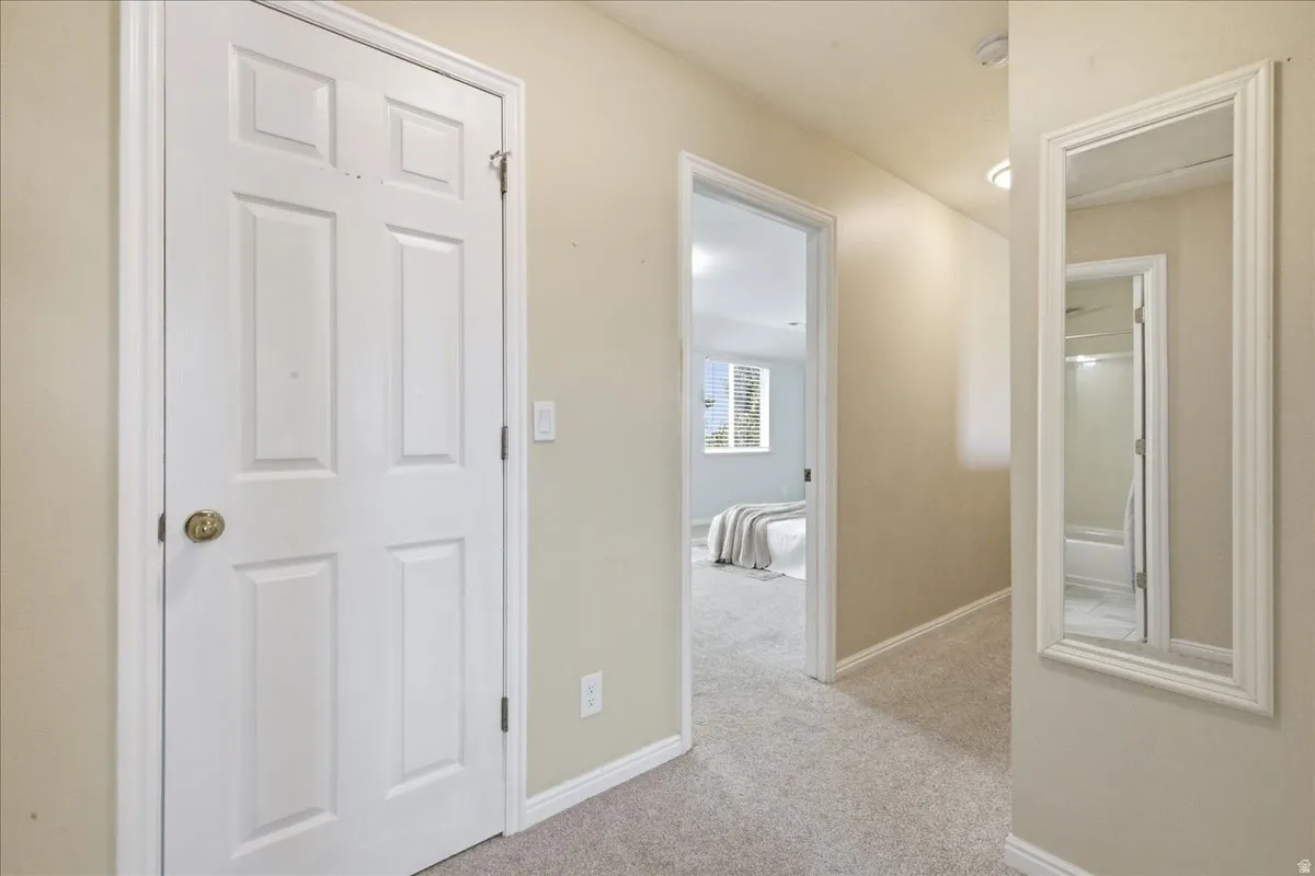 Carpeted hallway with painted walls, recessed lighting, and a framed wall mirror