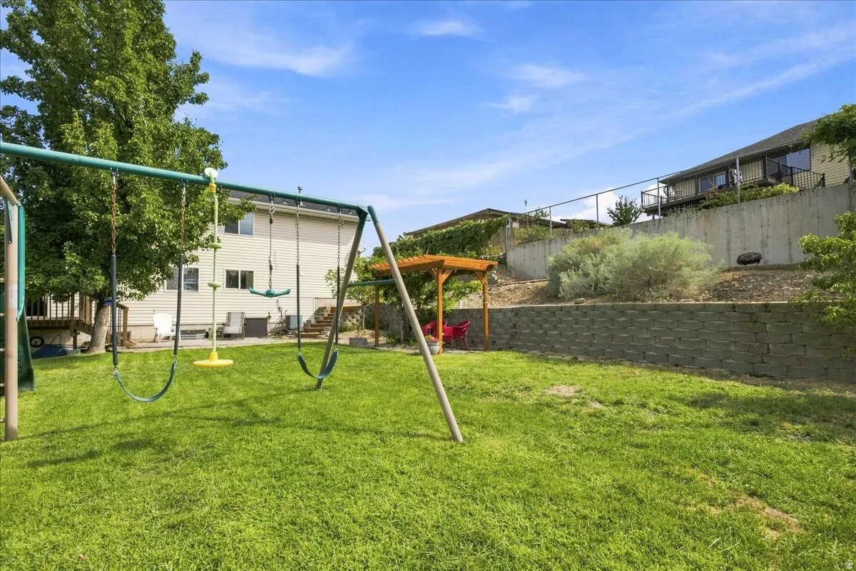Expansive lawn area with a built-in play structure and a wooden pergola