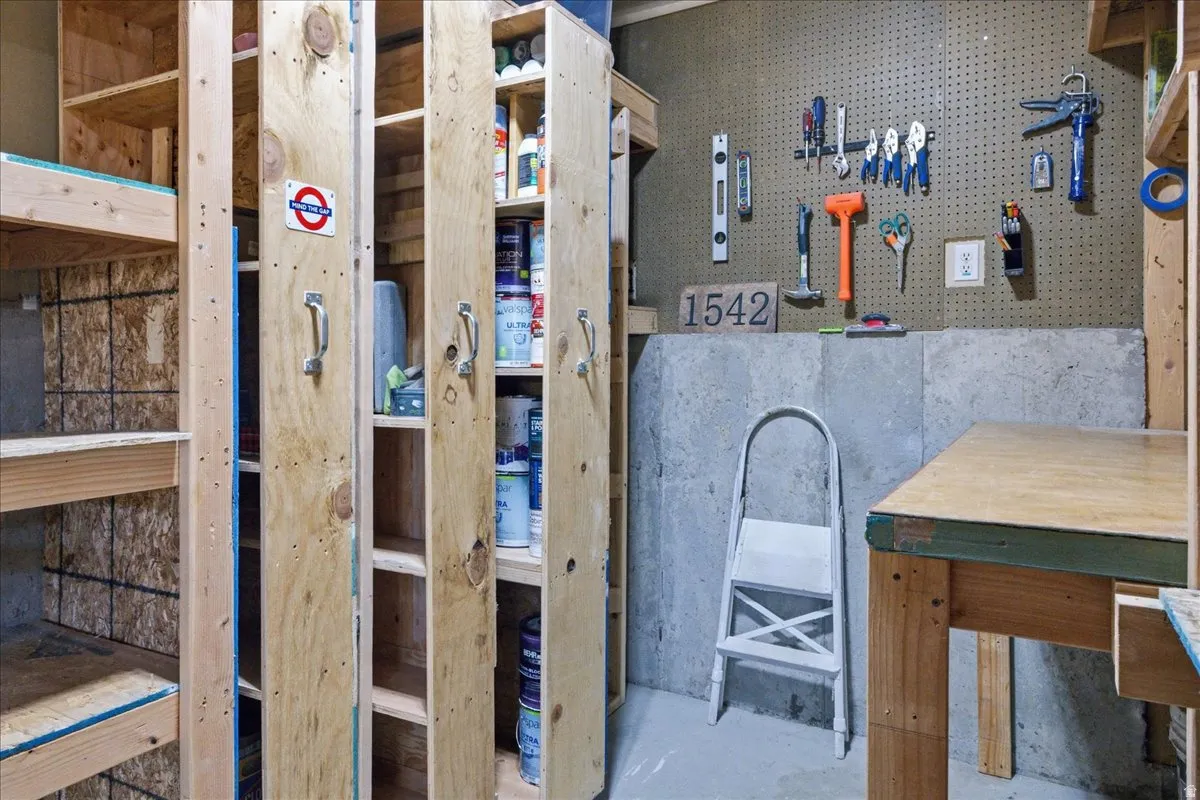 Built-in shelving, concrete foundation wall, pegboard storage system, wood-finish workbench