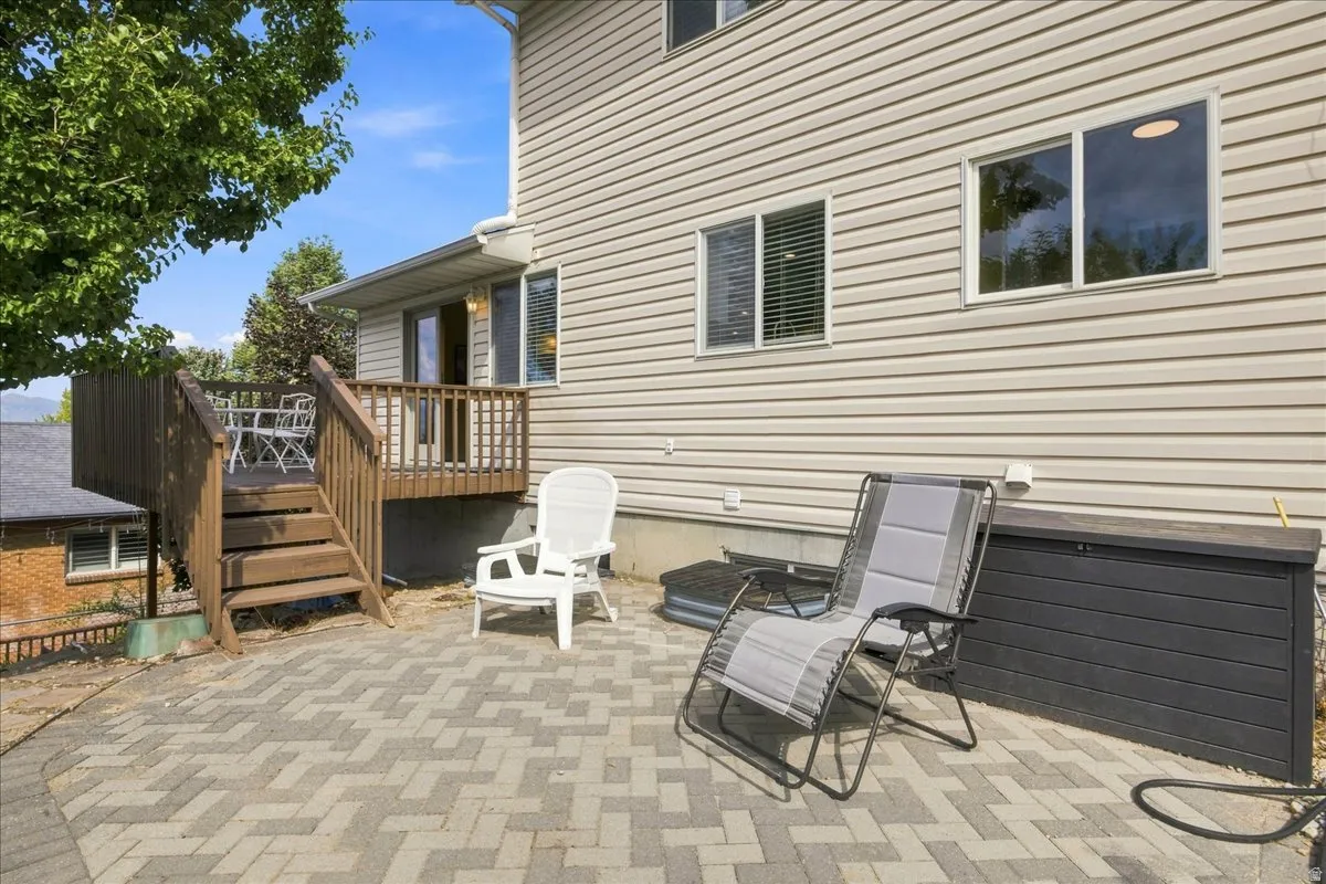 Patterned paver patio with a wood-tone deck and matching railings