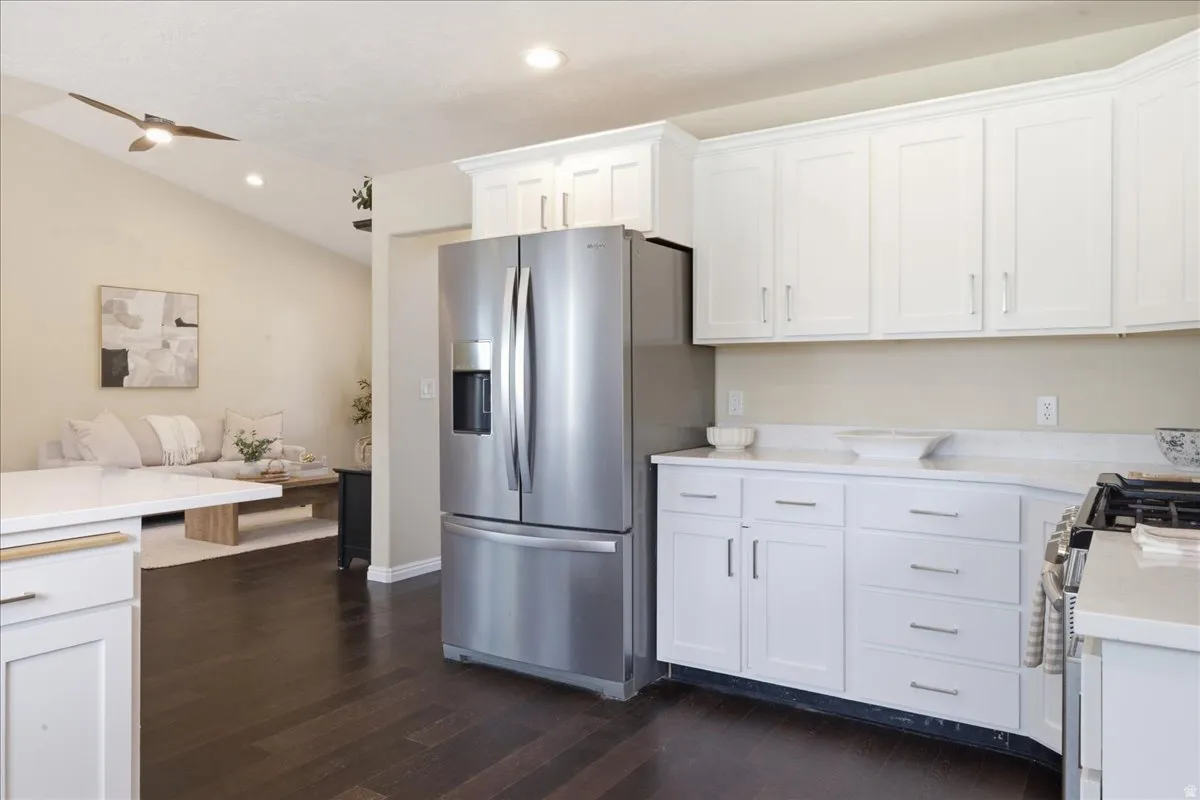 White cabinetry, wood-finish flooring, stainless steel refrigerator, white countertops, and recessed lighting