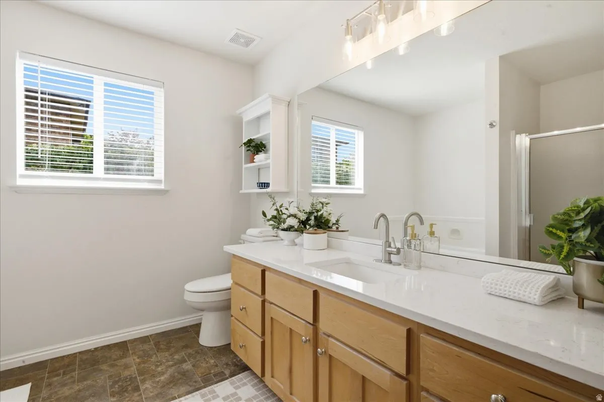 Dual-sink vanity with light wood-finish cabinetry, white countertop, and chrome fixtures