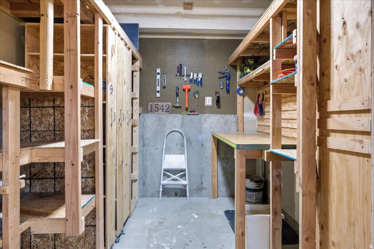Integrated workshop space featuring built-in shelving, a workbench, pegboard, and concrete flooring