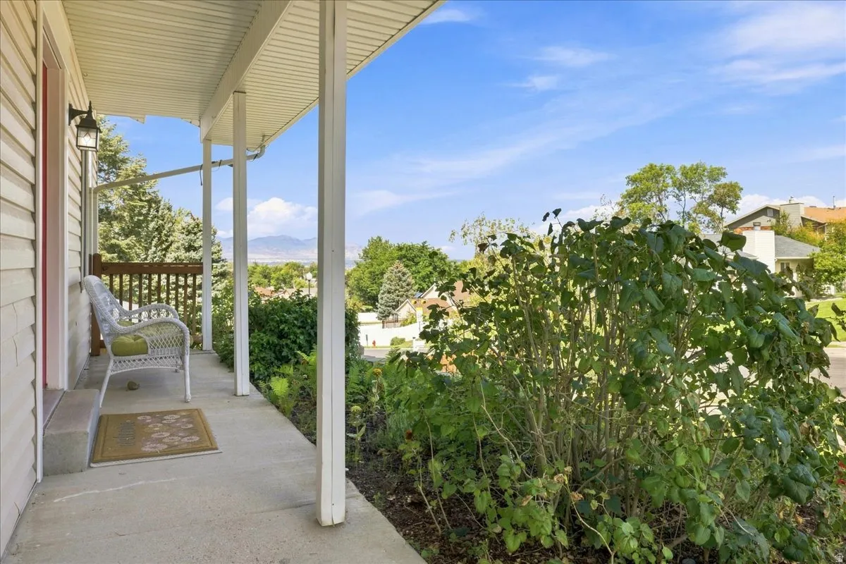 Front porch with concrete flooring, supported by white columns, featuring exterior siding and an attached outdoor light fixture