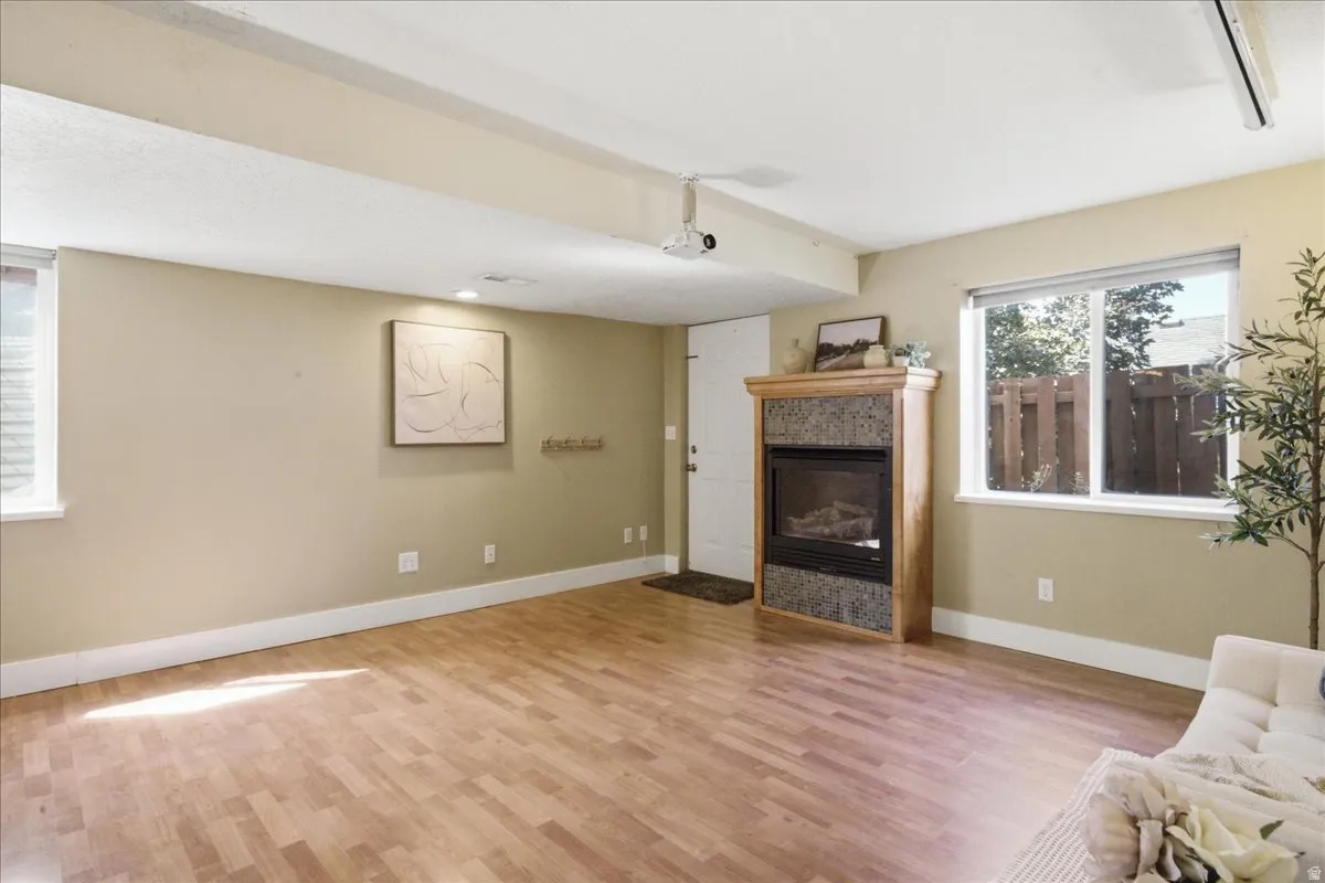 Wood-finish flooring, recessed lighting, and a stone-surround fireplace with a wood mantle
