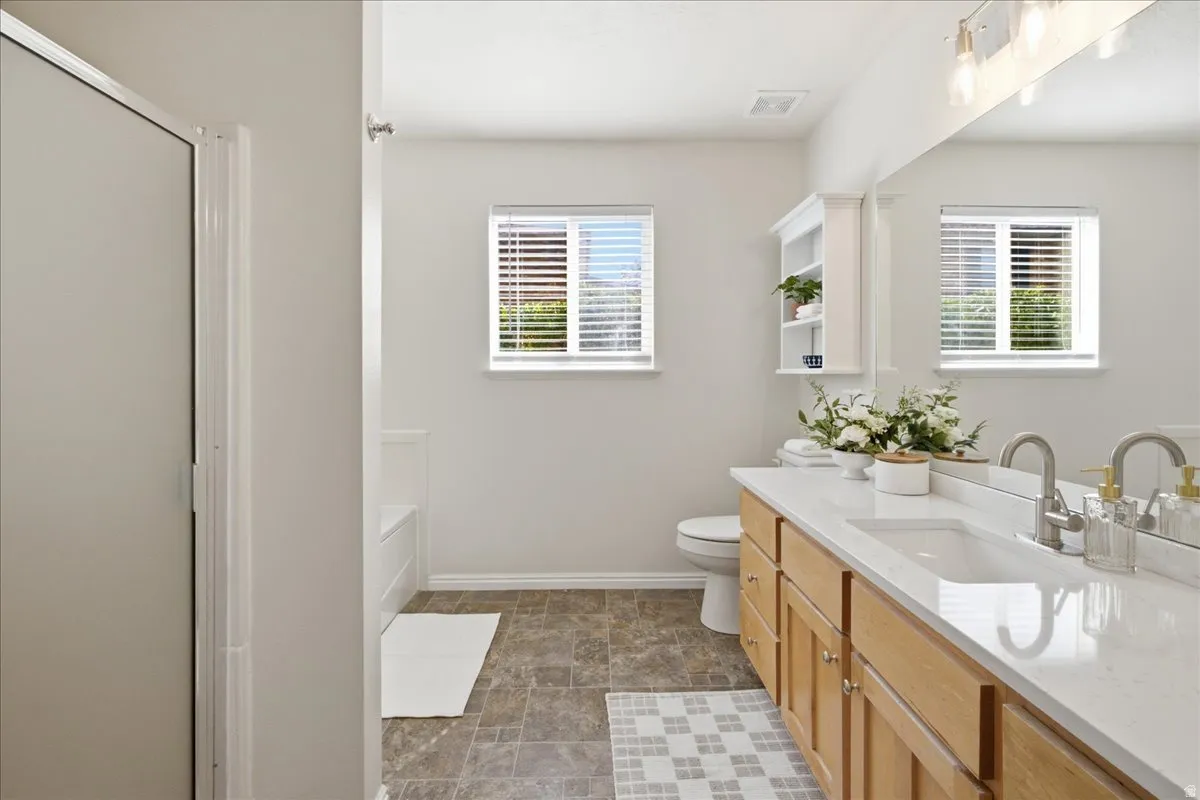 Dual-sink vanity with light wood-finish cabinetry, white countertop, and brushed nickel fixtures