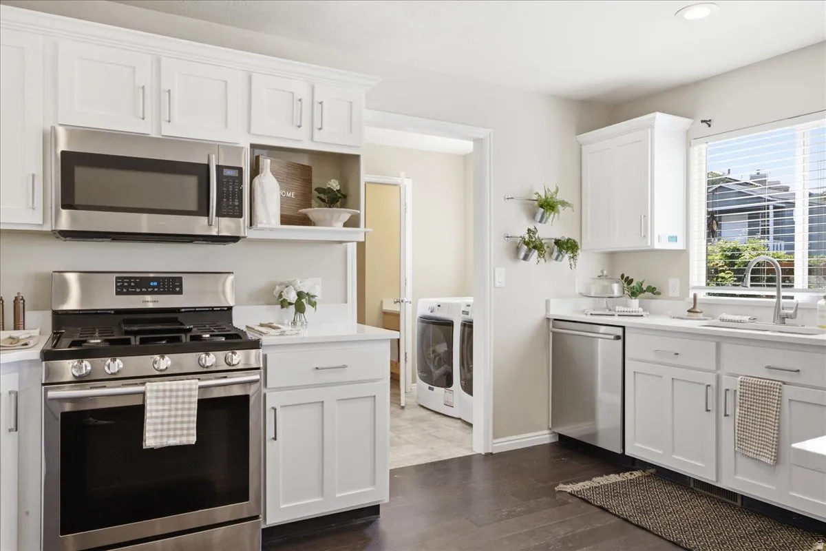 White shaker cabinetry with stainless steel appliances, white countertops, and wood-finish flooring