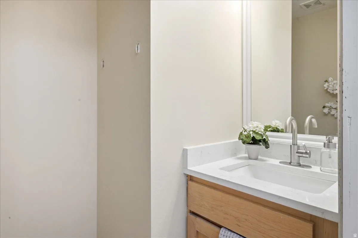 Built-in vanity with wood-finish cabinetry, a white countertop, and a single-basin sink featuring a brushed nickel faucet