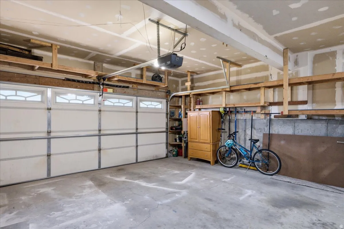 Spacious garage featuring a sectional garage door with decorative window inserts, concrete flooring, and built-in wood shelving