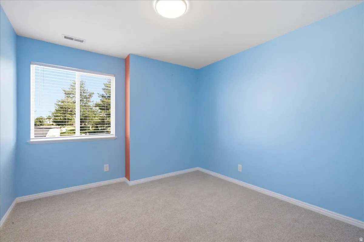 Recessed window with horizontal blinds, overhead flush mount lighting, and light-toned carpet