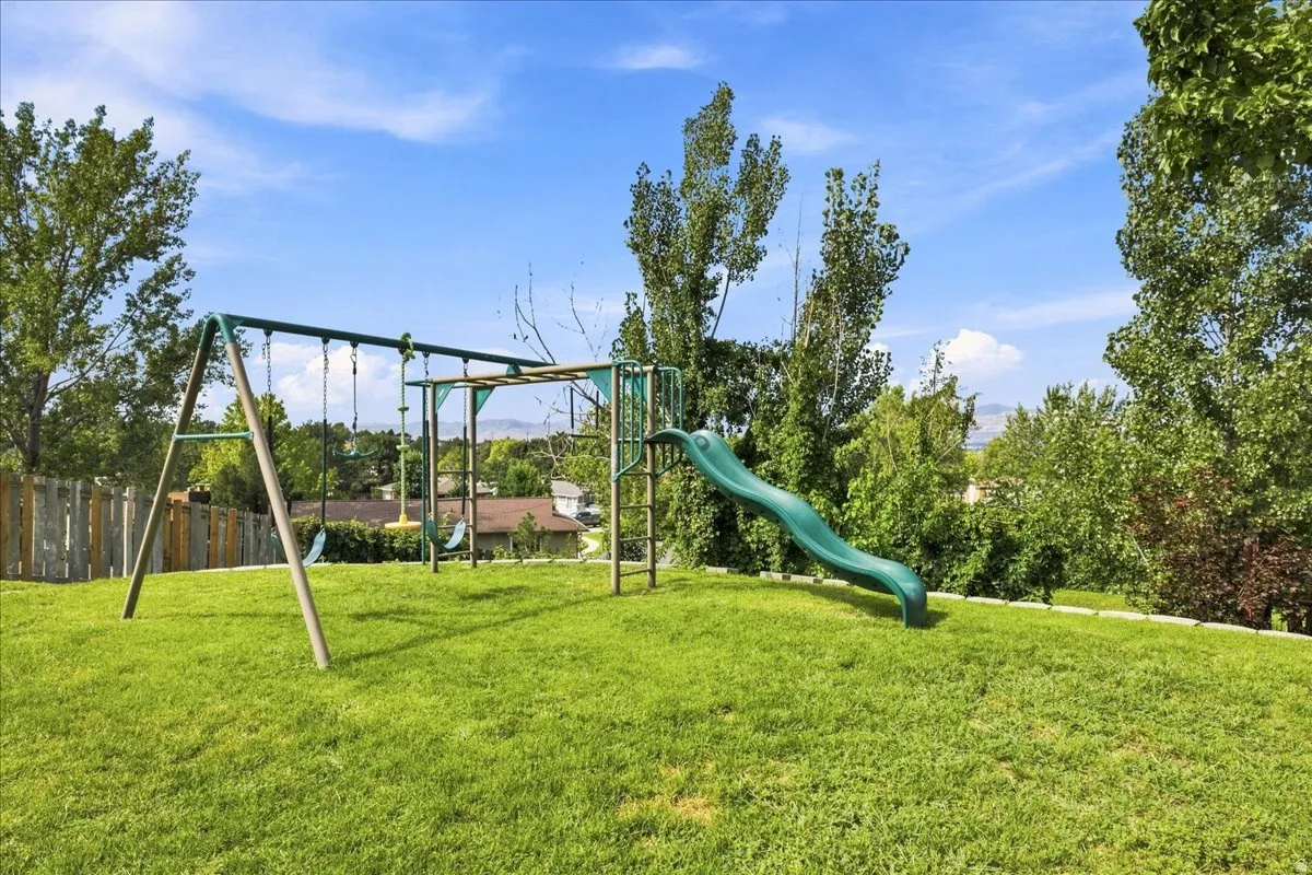 Expansive grassy lawn area featuring a swing set and a slide