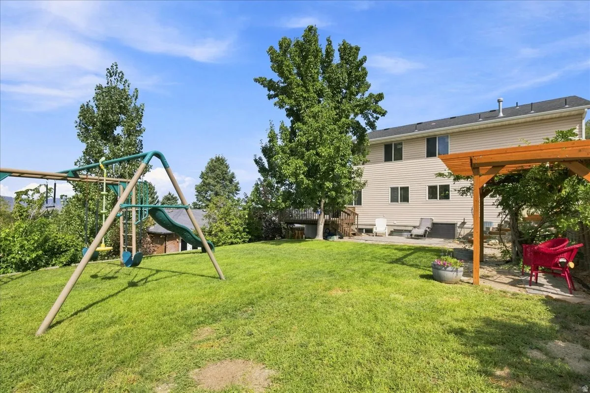 Expansive green lawn with mature trees, a wooden pergola, and a multi-level exterior