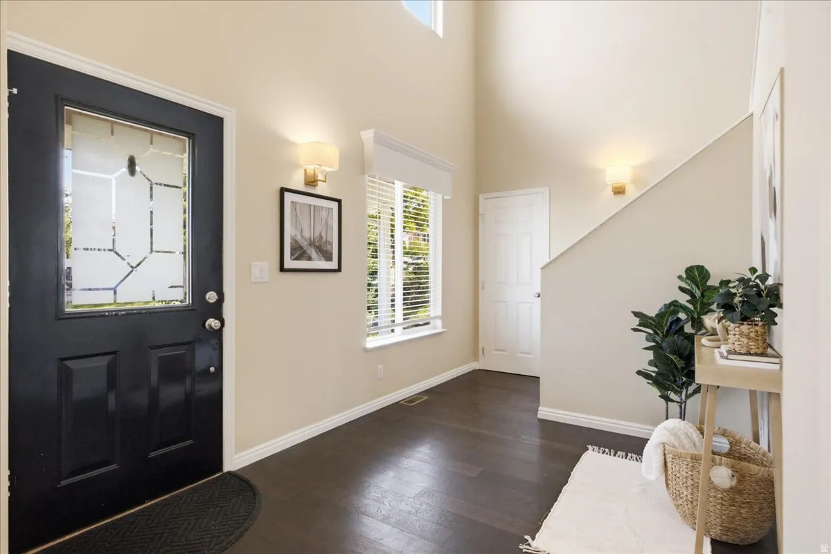 Entryway featuring a dark wood-finish floor, a black paneled door with decorative glass, and a high ceiling