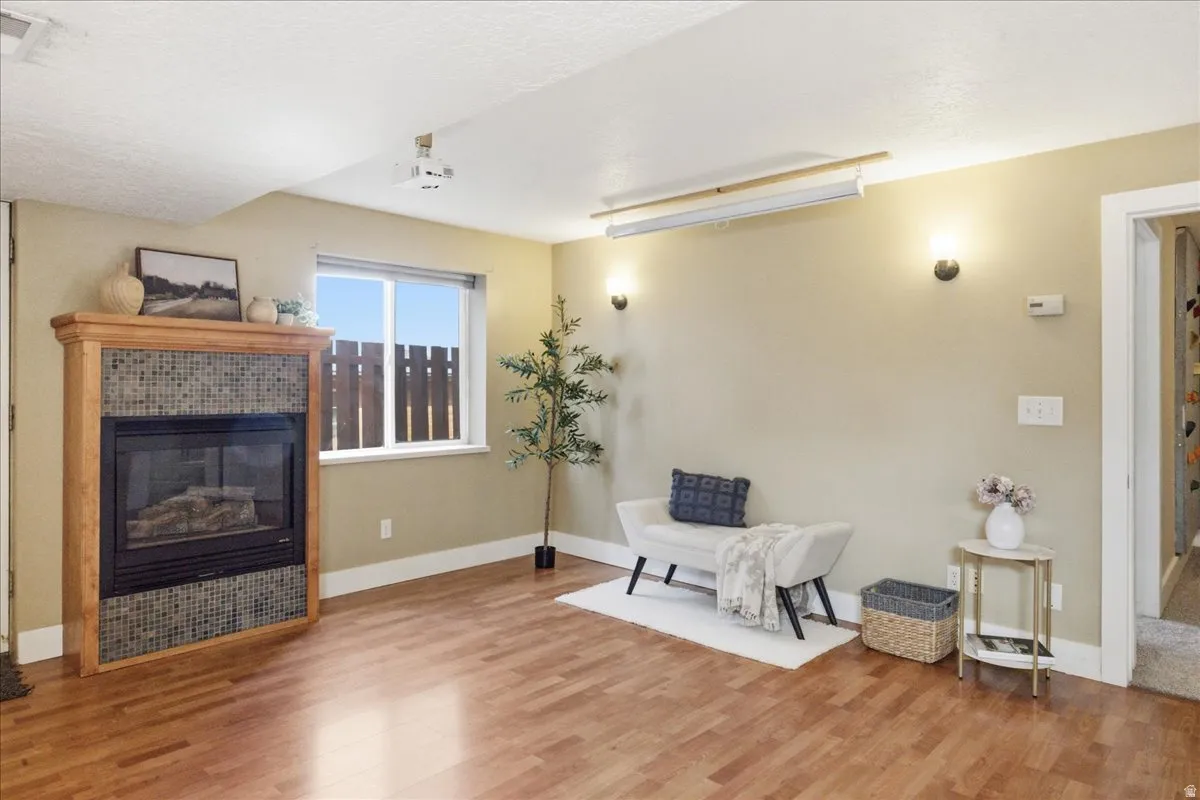 Wood-finish flooring throughout, featuring a fireplace with a mosaic tile surround and wood mantel