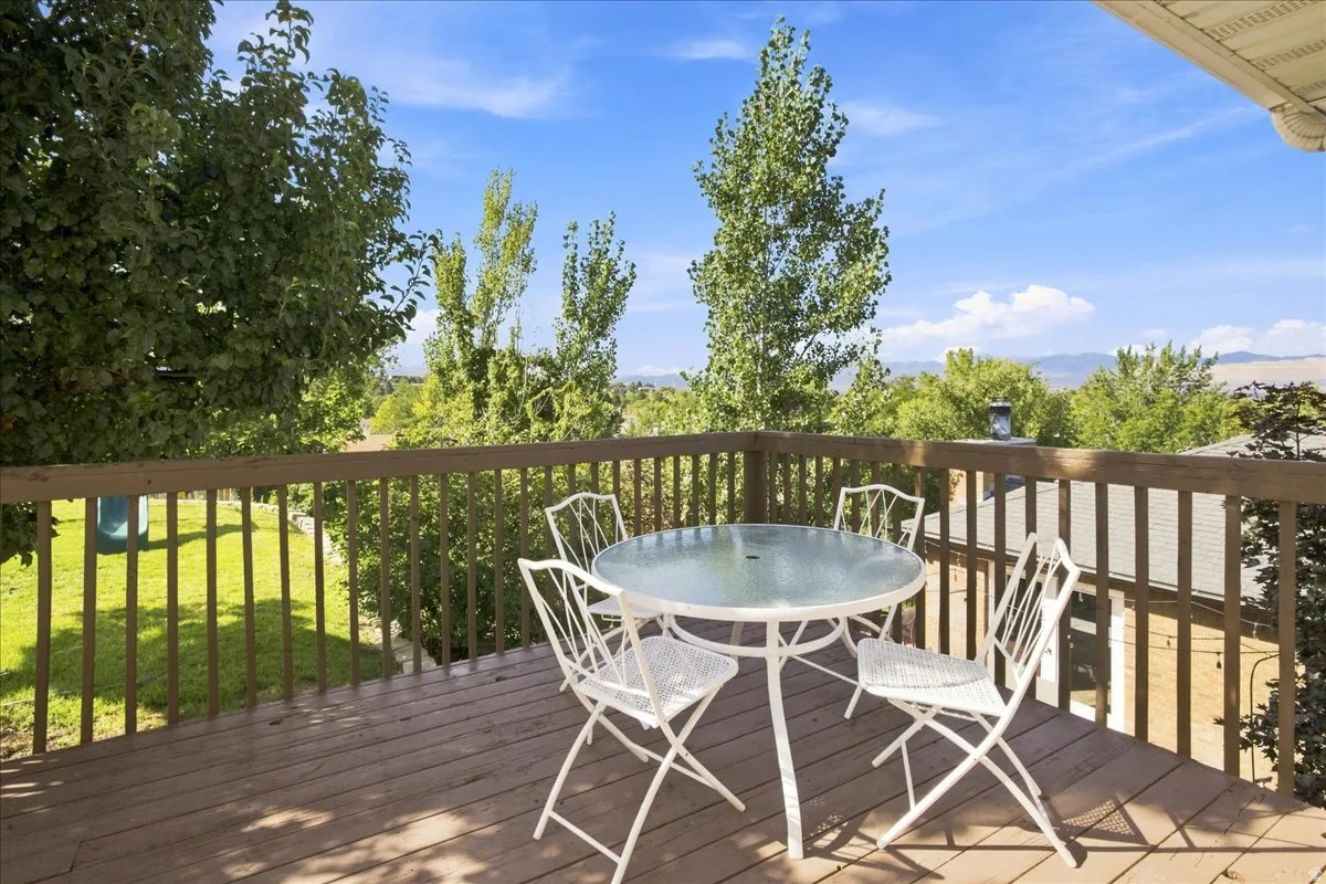 Outdoor wood-finish deck with wood railing, offering expansive tree-lined scenery