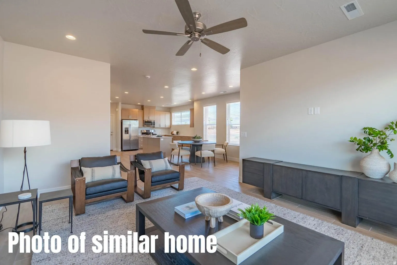 Open-concept living area with a ceiling fan, recessed lighting, and wood-finish flooring extending into the kitchen and dining area