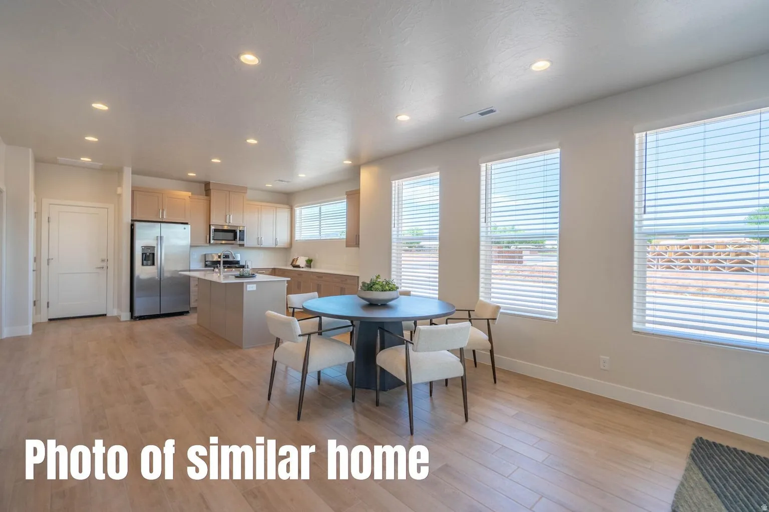 Open-concept living space featuring wood-finish flooring, recessed lighting, and multiple windows