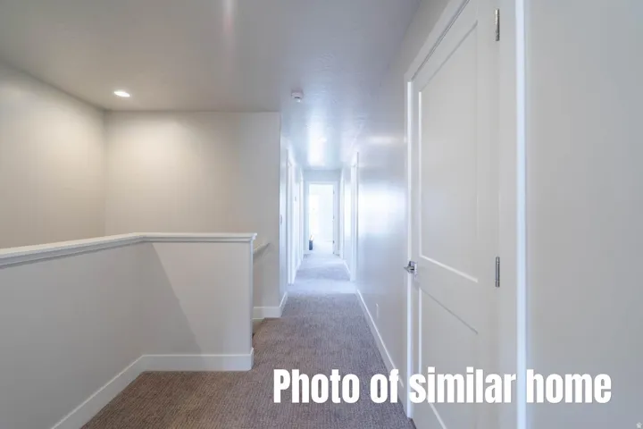Recessed lighting and a neutral color palette enhance this interior space featuring a hallway with panel doors and carpeted flooring